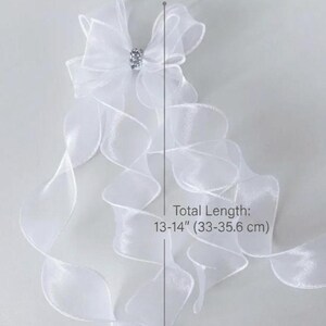 May include: White organza bow with a rhinestone center, 5 inches (12.7 cm) wide, and flowing ribbons. Total length is 13-14 inches (33-35.6 cm).