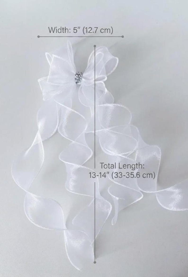 May include: White organza bow with a rhinestone center, 5 inches (12.7 cm) wide, and flowing ribbons. Total length is 13-14 inches (33-35.6 cm).