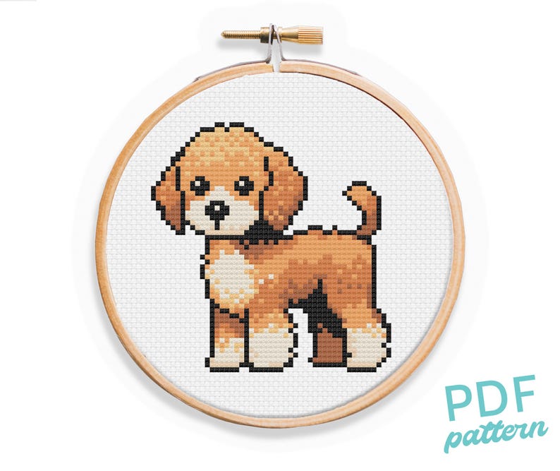 May include: Cross stitch pattern of a brown and white poodle dog in a wooden embroidery hoop. The pattern is for a PDF download.