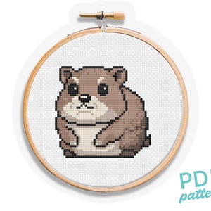 Könnte beinhalten: Kreuzstichmuster eines braunen Hamsters in einem hölzernen Stickrahmen. Der Hamster sitzt mit eingezogenen Pfoten und hat einen süßen Gesichtsausdruck. Das Muster ist im PDF-Format.