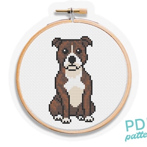 Puede incluir: Un patrón de punto de cruz de un perro marrón y blanco, exhibido en un bastidor de bordado de madera. El perro está sentado, con el pecho y la cara blancos y el cuerpo marrón. El texto "PDF pattern" está en la esquina inferior derecha.