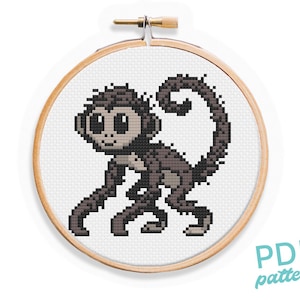 May include: Cross stitch pattern of a brown and gray monkey with big eyes. The monkey is sitting on its hind legs with its tail curled around its body. The pattern is in a wooden embroidery hoop.
