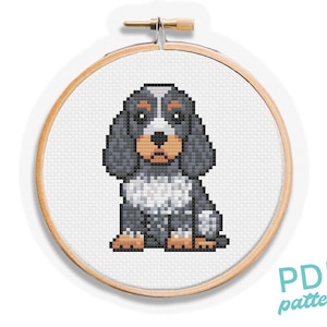 Op de afbeelding: Een kruissteekpatroon van een hond in een houten borduurring. De hond is afgebeeld in een pixelachtige stijl met grijze, witte en bruine kleuren. De tekst "PDF pattern" is zichtbaar in de rechter benedenhoek.