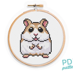 May include: A cross-stitch pattern of a cute hamster with brown fur, white cheeks, and pink ears. The hamster is sitting upright with its paws crossed in front of it. The pattern is displayed in a wooden embroidery hoop.