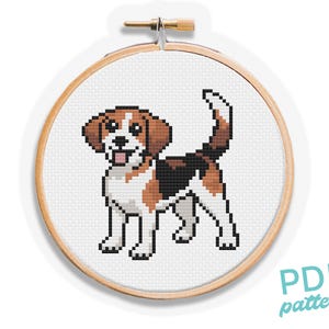 May include: A cross-stitch design of a beagle dog displayed in a wooden embroidery hoop. The dog is rendered in a pixelated style, featuring brown, black, and white hues. The text "PDF pattern" is visible in the lower right corner.