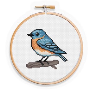May include: A bluebird with an orange breast is perched on a branch. The bird is cross-stitched on white fabric and framed in a wooden embroidery hoop.
