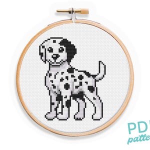 May include: Cross stitch pattern of a black and white Dalmatian dog in a wooden embroidery hoop. The pattern is for a PDF download.
