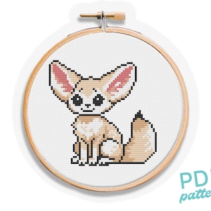 Puede incluir: Un patrón de punto de cruz con un lindo zorro fennec de dibujos animados con orejas grandes y ojos grandes. El zorro está sentado sobre un fondo blanco.