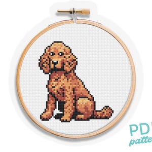 May include: A cross stitch pattern of a brown and white dog sitting with its ears perked up. The pattern is in a round wooden embroidery hoop. The text "PDF pattern" is in the bottom right corner of the image.
