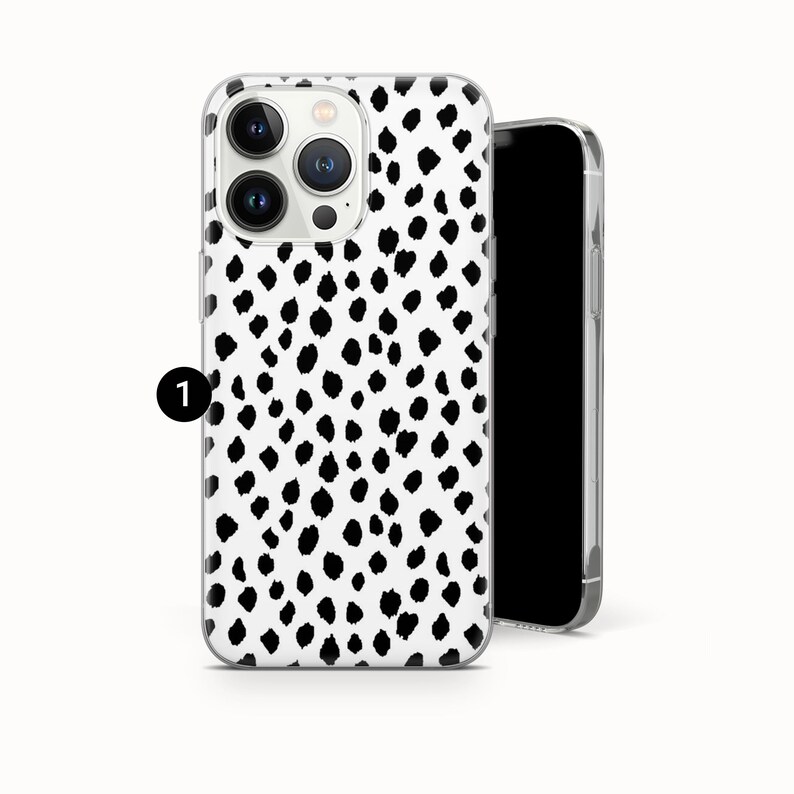 May include: A smartphone case featuring a white background with a repeating pattern of irregular black spots. The case has a cutout for a triple-lens camera system on the back. A black circle with the number 1 is positioned to the left of the case.