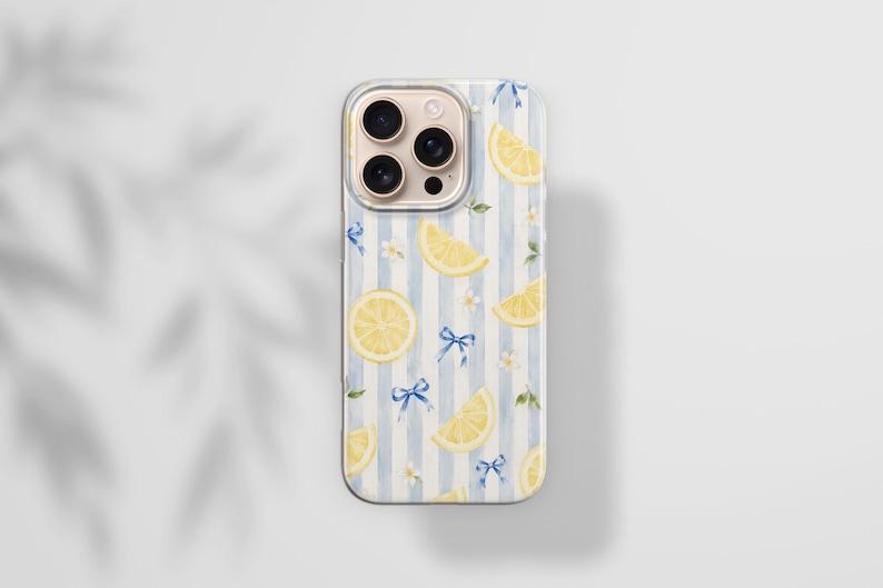 K&ouml;nnte beinhalten: Eine Smartphone-H&uuml;lle mit einem Muster aus gelben Zitronenscheiben, kleinen blauen Schleifen und winzigen wei&szlig;en Bl&uuml;ten auf einem Hintergrund aus vertikalen hellblauen und wei&szlig;en Streifen. Die H&uuml;lle hat einen Ausschnitt f&uuml;r eine Dreifachkamera.