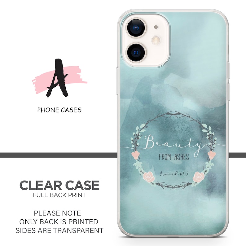 May include: A clear phone case with a watercolor background in shades of blue and pink. The case features a floral wreath with the text "Beauty from Ashes Isaiah 61:3".