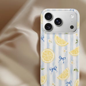 K&ouml;nnte beinhalten: Eine transparente Smartphone-H&uuml;lle mit einem Muster aus gelben Zitronenscheiben, kleinen wei&szlig;en Bl&uuml;ten und blauen Schleifen auf einem Hintergrund mit vertikalen hellblauen und wei&szlig;en Streifen. Die H&uuml;lle hat eine Aussparung f&uuml;r eine Dreifachkamera.