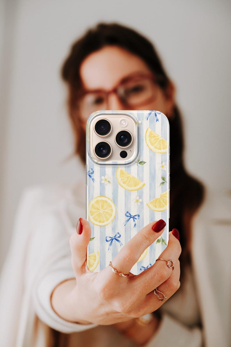 K&ouml;nnte beinhalten: Eine Smartphone-H&uuml;lle mit einem hellblau-wei&szlig; gestreiften Muster, das mit gelben Zitronenscheiben, kleinen wei&szlig;en Bl&uuml;ten und zarten blauen Schleifen verziert ist, die &uuml;ber die Oberfl&auml;che verteilt sind, inklusive Aussparung f&uuml;r die Kameralinse.
