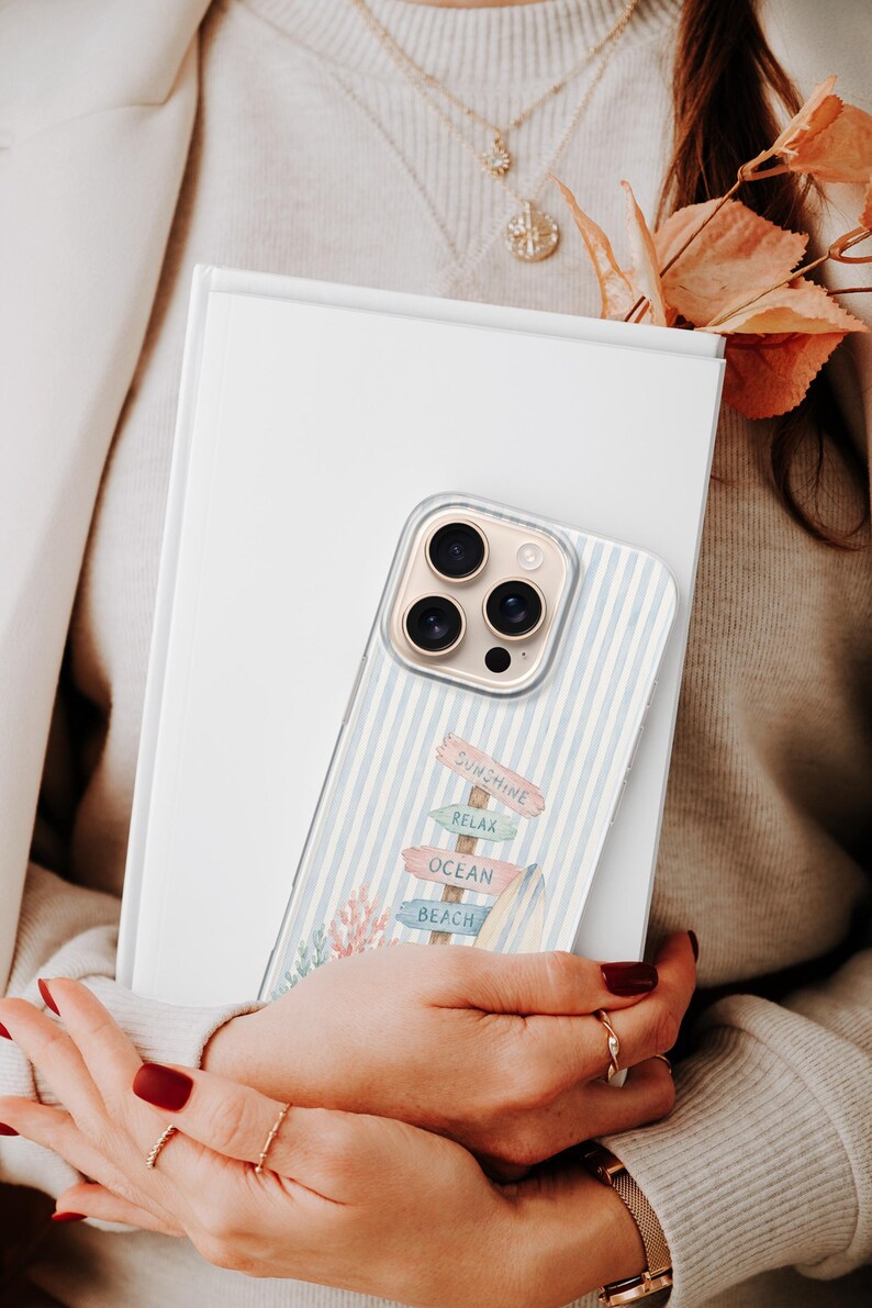K&ouml;nnte beinhalten: Eine transparente Smartphone-H&uuml;lle mit hellblau-wei&szlig;em vertikalem Streifenmuster und einer Grafik eines Holzschildes mit der Aufschrift Sunshine, Relax, Ocean und Beach, erg&auml;nzt durch ein Surfbrett und korallenfarbenes Blattwerk.