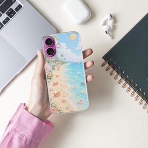 K&ouml;nnte beinhalten: Eine transparente Smartphone-H&uuml;lle mit einer farbenfrohen Strandillustration, die Sand, blaues Meer, Palmen, kleine Krabben, Seesterne und rosa Blumen zeigt. Die H&uuml;lle hat einen markanten violetten Kamerarahmen und ein leuchtend gelbes Sonnensymbol.