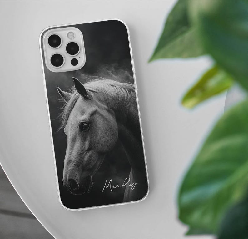 May include: A phone case featuring a black and white image of a horse's head. The image has a soft, artistic quality. The case has a clear border and the name "Mandy" is written in cursive at the bottom.