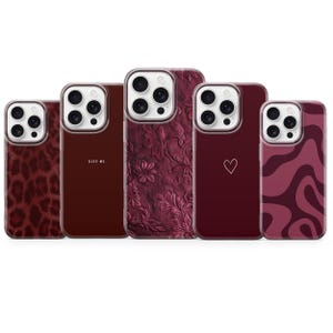 Może przedstawiać: Kolekcja pięciu etui na telefony w odcieniach bordowego i kasztanowego. Wzory obejmują nadruk w cętki, napis "KISS ME.", wzór kwiatowy, kontur serca i falisty wzór. Każde etui ma przezroczystą obwódkę.