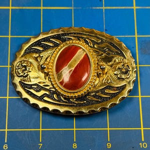 Oval shaped western style gold colored alloy metal belt buckle with a red Brazilian agate centerpiece sadly carved on the backsee pics read