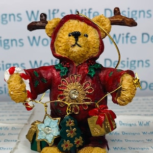 Cute little Christmas bear in onesie with antlers holding garland Christmas bear ornament