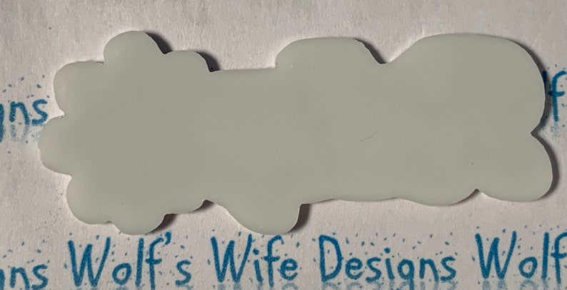 May include: A white, blank, vinyl sticker with a slightly irregular, cloud-like shape.