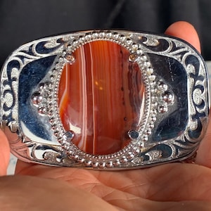 Red lined agate in a rectangular metal silver colored buckle has etched scrolling has scratch on the metal please look at photos