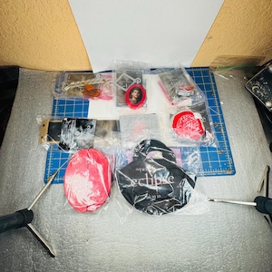 Puede incluir: Una colección de artículos de merchandising de la película Twilight Eclipse sellados en envases de plástico transparente, incluyendo una bolsa de tela negra con el texto 'the twilight saga eclipse 06.30.10', un objeto rojo con forma de cerebro, un llavero y varias tarjetas.