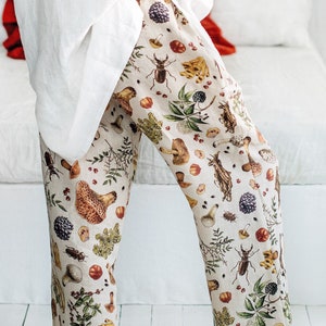 May include: White linen trousers with a beige background and a colourful print of mushrooms, insects, and plants.