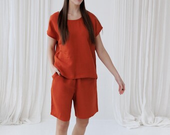 Puede incluir: Una mujer con un top de lino color óxido y pantalones cortos a juego. El conjunto es holgado y cómodo, perfecto para el clima cálido.