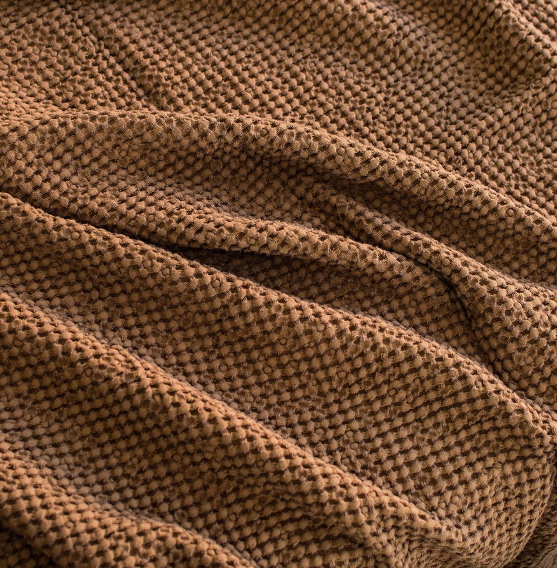 May include: A close-up of a brown textured fabric with a waffle-like pattern. The fabric is soft and has a subtle sheen.