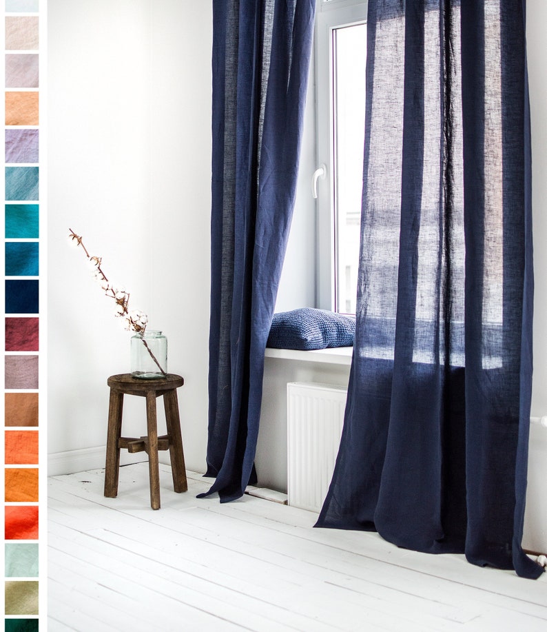 May include: A pair of dark blue linen curtains hang in a window, with a white windowsill and a white radiator underneath. The curtains are gathered at the top and hang straight down, with a slight ripple in the fabric. The curtains are made of a natural linen fabric and have a simple, elegant design.
