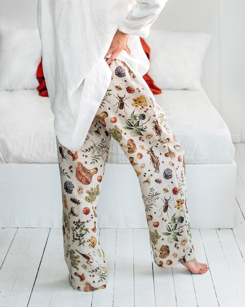May include: White linen trousers with a beige background and a colourful print of mushrooms, insects, and plants.