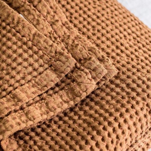 Pu&ograve; includere: Una coperta in tessuto a nido d'ape marrone con una superficie testurizzata.