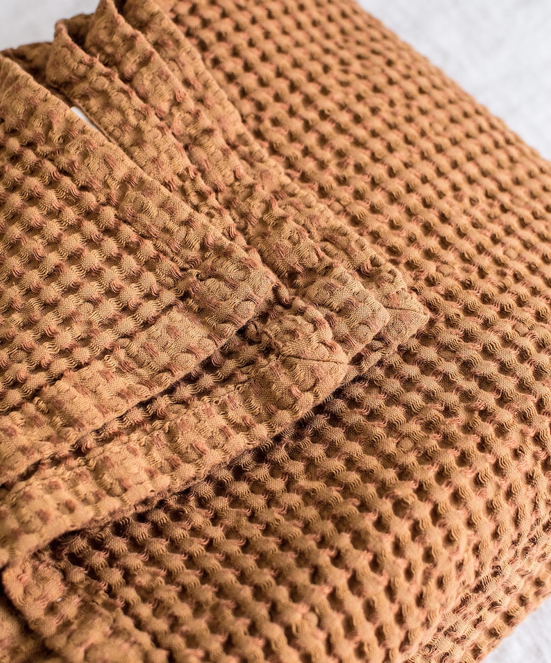 Pu&ograve; includere: Una coperta in tessuto a nido d'ape marrone con una superficie testurizzata.