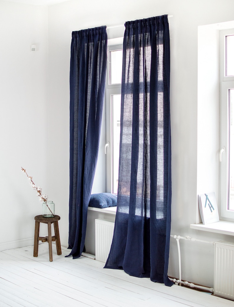 May include: A pair of dark blue linen curtains hanging in a window. The curtains are long and flowing, and they are made of a soft, natural fabric.