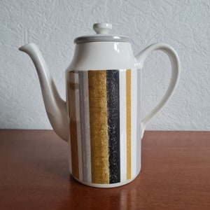 May include: A white ceramic coffee pot with a grey lid and a striped design in shades of grey, gold, and black.