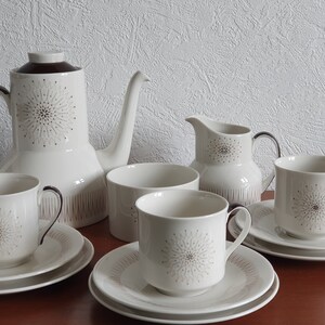 May include: A white and brown ceramic tea set with a geometric pattern. The set includes a teapot, creamer, sugar bowl, and four cups and saucers.