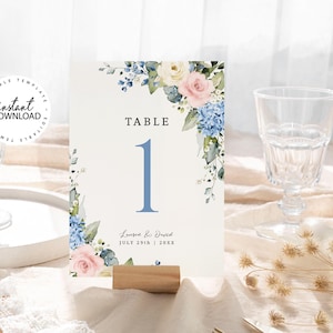 May include: A white table number card with blue and pink watercolor flowers. The card says "Table 1" and "Lauren & David July 29th | 20XX".