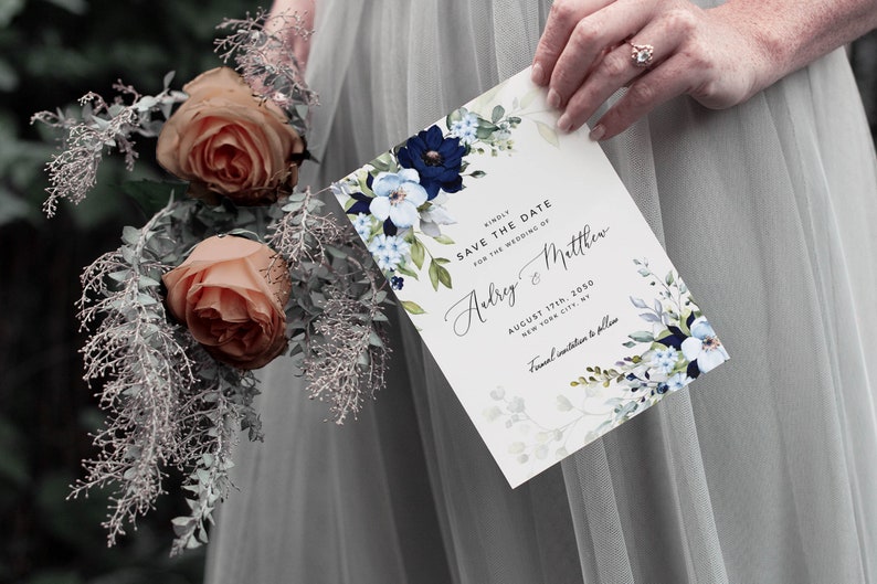 May include: A white save the date card with blue and white floral illustrations. The text reads "Kindly save the date for the wedding of Audrey & Matthew, August 17th, 2050, New York City, Formal invitation to follow."