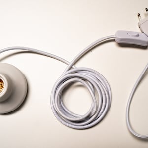 May include: White electrical cord with a white inline switch and a white plug. The cord is coiled and has a white ceramic light socket at the end.