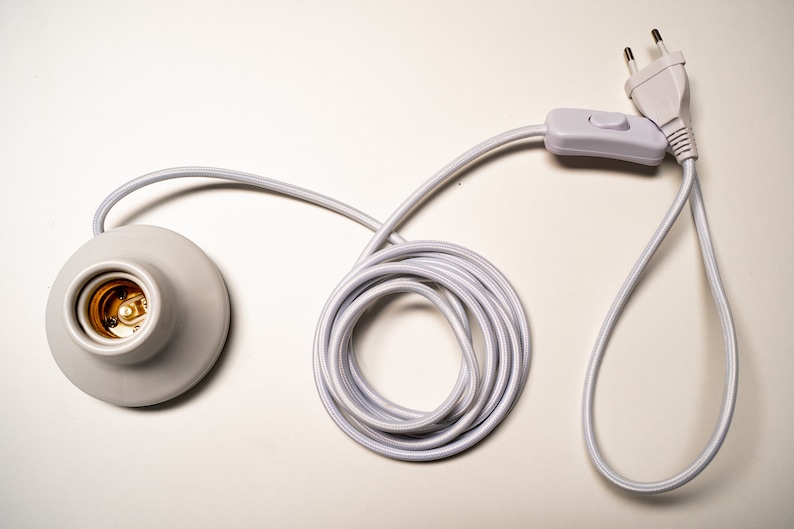 May include: White electrical cord with a white inline switch and a white plug. The cord is coiled and has a white ceramic light socket at the end.