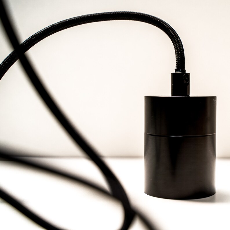 K&ouml;nnte beinhalten: Schwarzes Pendelleuchtenkabel mit einer schwarzen Deckenleuchte aus Metall.