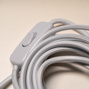 May include: Close-up of a gray inline switch on a coiled gray cord.
