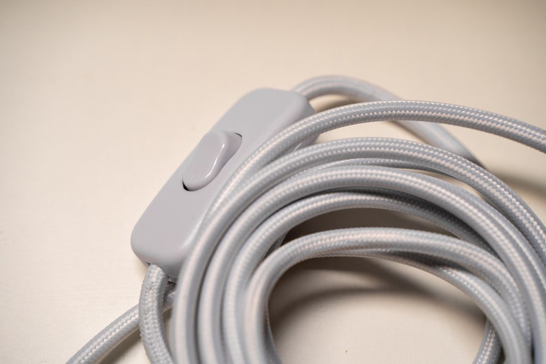 May include: Close-up of a gray inline switch on a coiled gray cord.