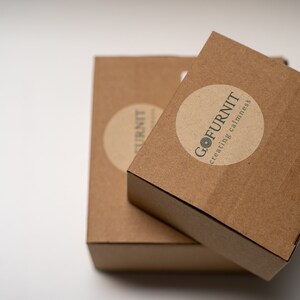 May include: Two brown cardboard boxes stacked on top of each other. The top box has a round sticker with the text "GO FURNIT creating calmness".