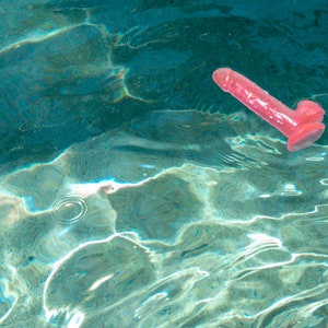 May include: A pink rubber toy floating in a blue pool of water.