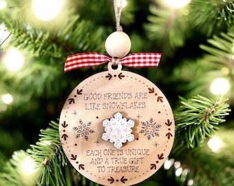 May include: A round wooden ornament featuring the engraved text "GOOD FRIENDS ARE LIKE SNOWFLAKES EACH ONE IS UNIQUE AND A TRUE GIFT TO TREASURE." The ornament includes a small white snowflake cutout, a red and white gingham ribbon, and a bead.