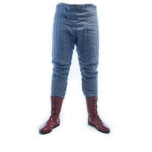 May include: Grey quilted trousers with brown leather boots. The trousers have a loose fit and are made of a thick, durable fabric.