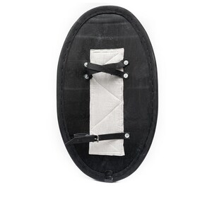 May include: Black oval shield with a white padded strap and metal rivets. The shield is made of leather and has a strap for carrying.