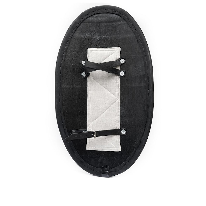 May include: Black oval shield with a white padded strap and metal rivets. The shield is made of leather and has a strap for carrying.